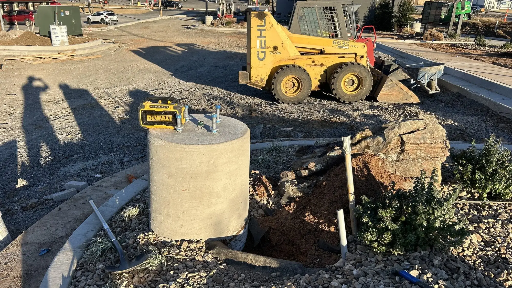 A skid steer and open excavation on a street-side job site